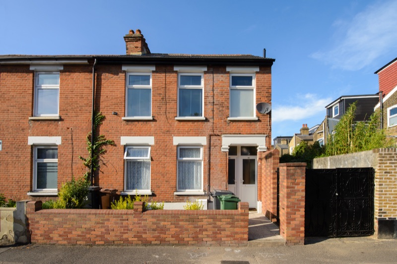 A restored end of terrace house with a brick front garden wall